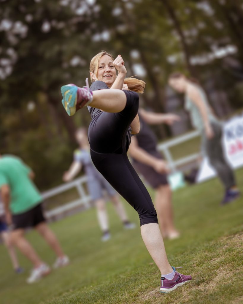 Karate-Einsteigerin im Sportoutfit führt eine Beintechnik (Masashi-Geri) aus